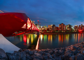 Illuminated peace bridge over bow river in city at night