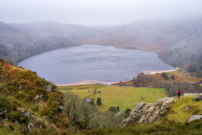 High angle view man standing on cliff against lake