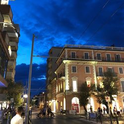 People on street amidst buildings in city at dusk