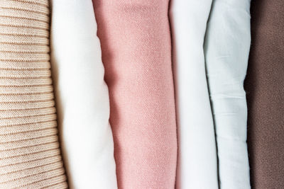 A stack of folded multicolored sweaters close up top view.