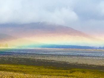 Scenic view of rainbow over sea against sky