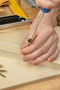 Close-up of craftsperson using screwdriver on wooden plank