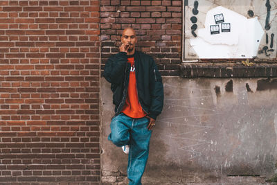 Man standing against brick wall