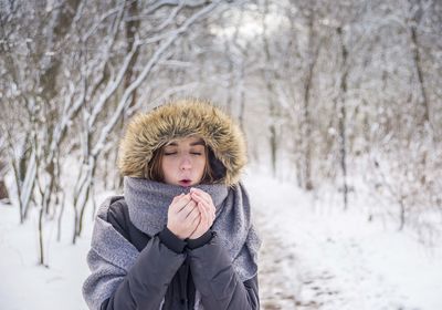 Girl standing snow covered land against trees