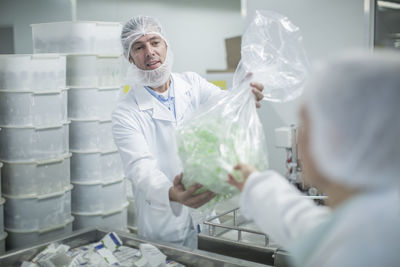 Lab worker in pharmaceutical plant handing over plastic bag