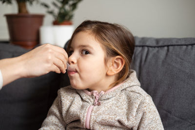 Cropped hand of mother feeding medicine to daughter 