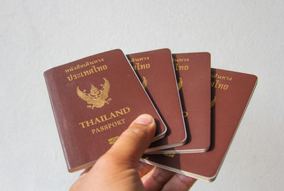 Cropped hand holding passports against wall