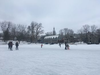 People on snow covered landscape with buildings in background