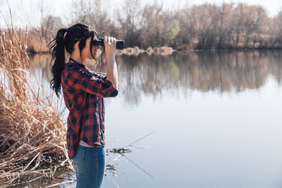 Woman looking at lake through binoculars