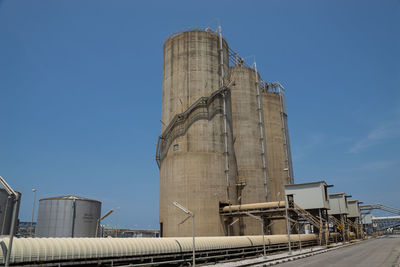 Low angle view of factory against clear blue sky