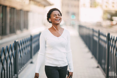 Smiling young woman standing against railing