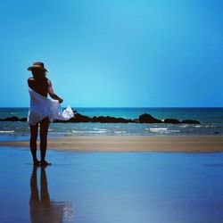 Rear view of semi nude woman with sarong standing on beach