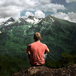 Rear view of man looking at mountain against sky