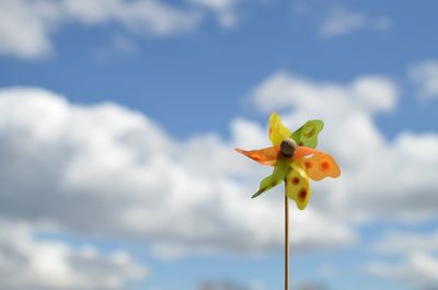 Low angle view of pinwheel against cloudy sky