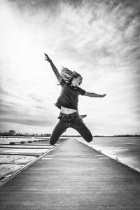 Low angle view of woman jumping against sky