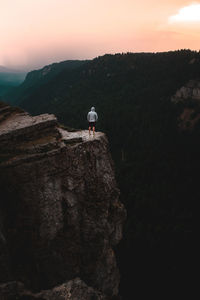 Full length of man standing by cliff against sky during sunset