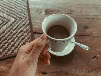 Hand holding coffee cup on table