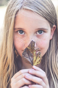 Close-up portrait of girl holding leaf