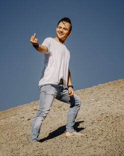 Full length of young man standing on land against clear sky