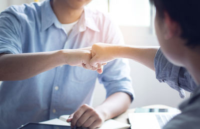 Close-up of business colleagues bumping fist in office