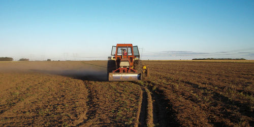Tractor on agricultural field against clear sky