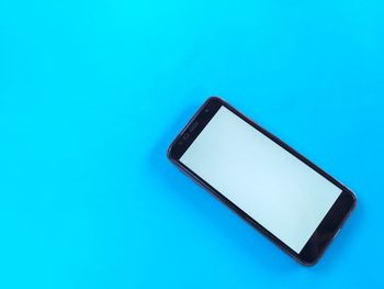 Close-up of smart phone on blue table