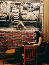 Shadow of woman sitting on chair against wall