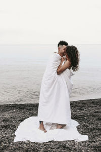 Couple kissing on beach against sky