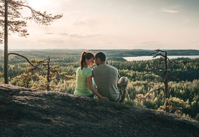 Rear view of couple sitting on land against sky