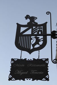 Low angle view of weather vane against sky