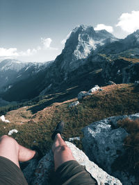 Low section of person on mountain against sky