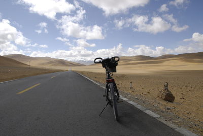 Bicycle parked on road at desert