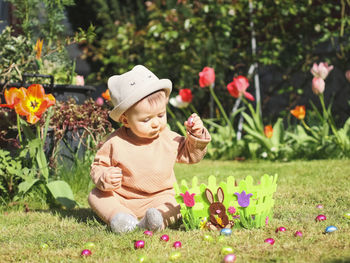 Happy baby girl with easter chocolate egg on the lawn.