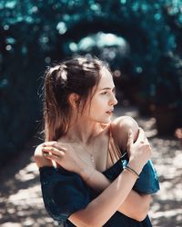 Young woman looking away while standing on road