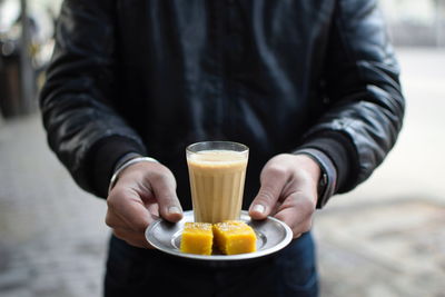 Close-up of hand holding drink served on table