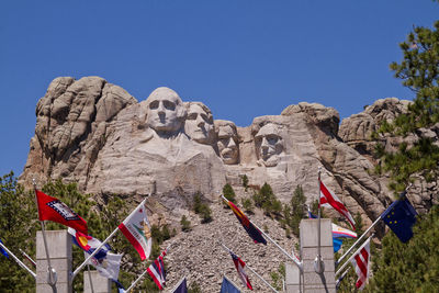 Low angle view of flags at mt rushmore national monument against clear sky