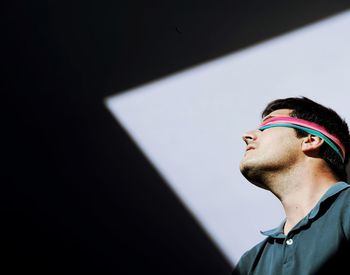 Low angle view of man with fabric on eyes against wall