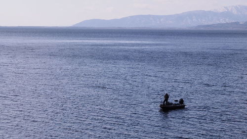 People on sea against mountain