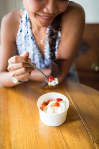 Midsection of woman with ice cream in bowl