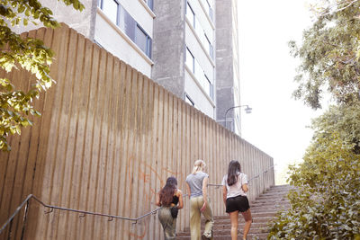 Rear view of three women walking up stairs