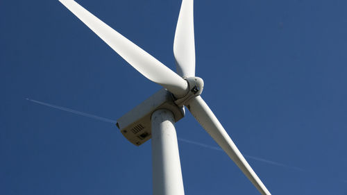 Low angle view of wind turbine against blue sky