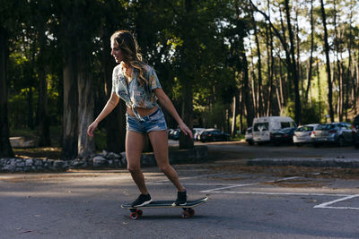 Beautiful skater practicing riding skate board on street near camping