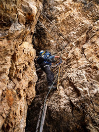 Low angle view of senior man climbing on rocky mountain