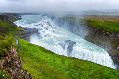 Scenic view of waterfall against sky 