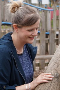 Smiling woman standing by wooden structure at park