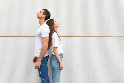 Young couple standing against wall