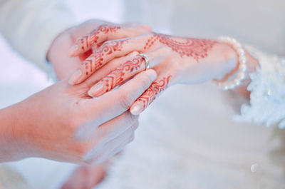 Cropped hand of groom putting ring in bride finger during wedding ceremony

