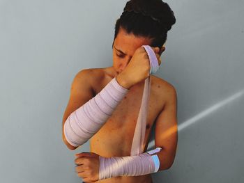 Midsection of young woman standing against wall