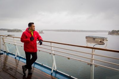 Side view of man standing on port-side of ferry
