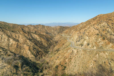 Scenic view of arid landscape against clear blue sky